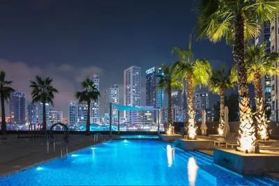 a swimming pool with a city skyline at night at Stylish 1BR in Sparkle Towers Dubai Marina Escape in Dubai