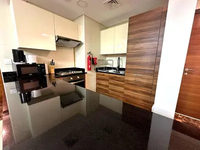 a small kitchen with wooden cabinets and a stove at Stylish 1BR in Sparkle Towers Dubai Marina Escape in Dubai