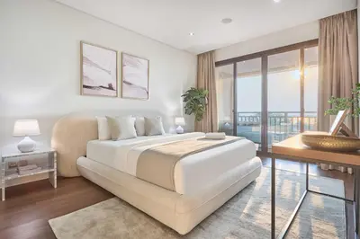 a white bedroom with a bed and a balcony at Royal Amwaj Palm Jumeirah - Luxury 1BR with Pool and Gym in Dubai