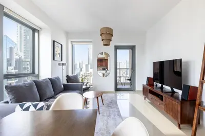 a living room with a couch and a tv at Elegant 2BR Balcony and Stunning Burj Views in Dubai