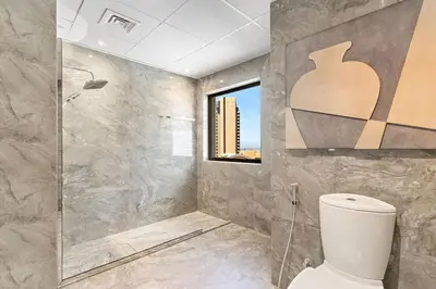 a bathroom with a toilet and a shower and a window at The Smart Concierge - Murjan 5 in Dubai