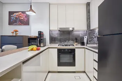 a kitchen with white cabinets and a stove top oven at Nobles Tower Business Bay - Modern 1-Bedroom Apartment in Dubai