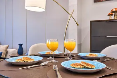 a table with plates of food and glasses of orange juice at Nobles Tower Business Bay - Modern 1-Bedroom Apartment in Dubai