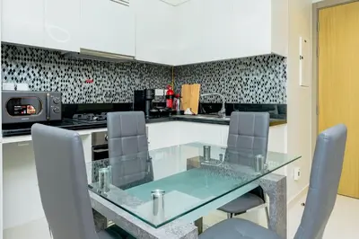 a kitchen with a glass table and chairs at Nasma Luxury stays- Lavish with luxury facilities in Aykon city in Dubai