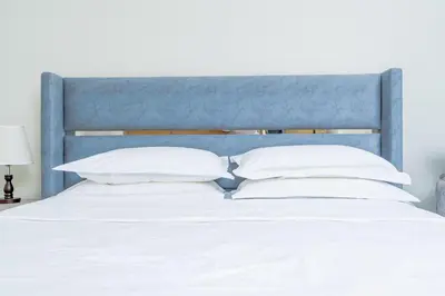 a bed with a blue headboard and white pillows at Nasma Luxury stays- Lavish with luxury facilities in Aykon city in Dubai