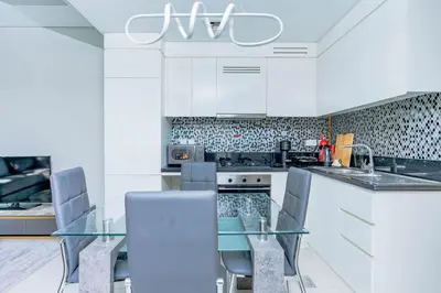 a kitchen with a glass table and white cabinets at Nasma Luxury stays- Lavish with luxury facilities in Aykon city in Dubai