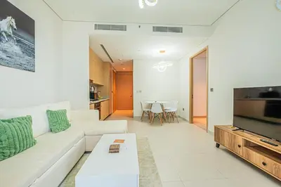 a living room with a white couch and a television at Vida Dubai Mall 1BR apt - Connected to Dubai Mall in Dubai