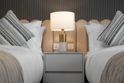 a lamp on a night stand next to two beds at Paramount 59th Floor , Burj View Infinity Pool in Dubai