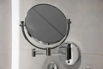 a round mirror on a wall in a bathroom at Paramount 59th Floor , Burj View Infinity Pool in Dubai