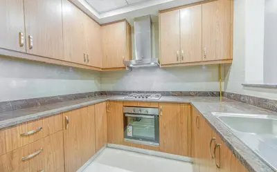 a kitchen with wooden cabinets and a sink at Cozy and modern 1 BR Apt in Al Furjan in Dubai