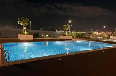 a swimming pool on the roof of a building at night at Homely Bliss Studio in Azizi Riviera-12 in Dubai