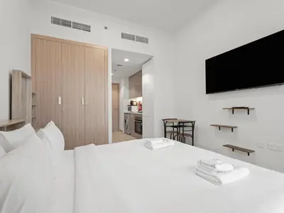a bedroom with a white bed with a flat screen tv at Homely Bliss Studio in Azizi Riviera-12 in Dubai