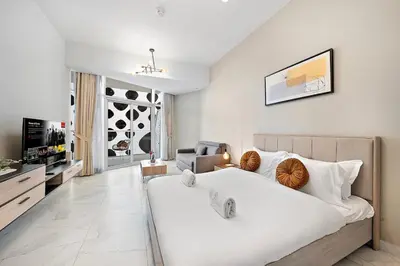 a white bedroom with a large bed and a living room at FIRST CLASS Studio Canal & Burj Khalifa View in Dubai