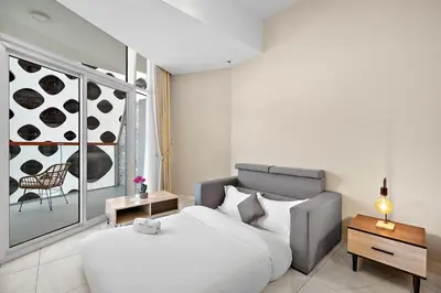 a bedroom with a large white bed and a chair at FIRST CLASS Studio Canal & Burj Khalifa View in Dubai