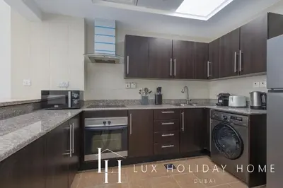 a kitchen with wooden cabinets and a washer and dryer at LUX The 02 Residences JLT Suite in Dubai