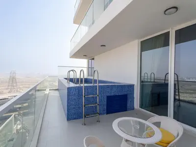a balcony with a table and chairs on a building at Exclusive Gemz Stay 2BR plus Study w Private Pool-07 in Dubai