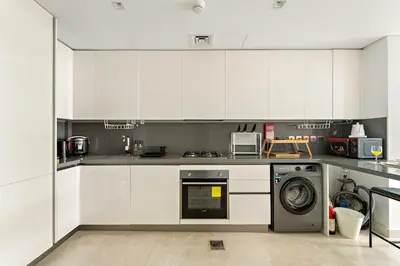 a kitchen with white cabinets and a washing machine at FIRST CLASS 2BR Modern Luxury Hideaway in Dubai