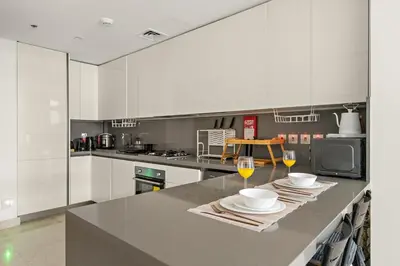 a kitchen with white cabinets and a counter with two glasses of wine at FIRST CLASS 2BR Modern Luxury Hideaway in Dubai