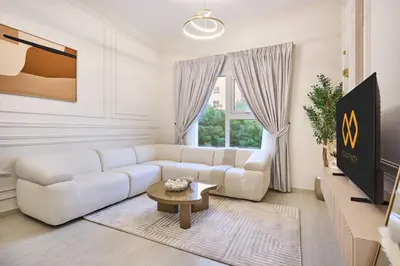 a white living room with a white couch and a table at Modern 2-Bedroom Retreat in Remraam - Al Ramth 5 in Dubai