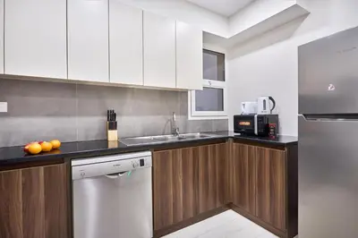 a kitchen with white cabinets and a stainless steel refrigerator at Modern 2-Bedroom Retreat in Remraam - Al Ramth 5 in Dubai