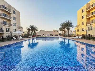 a large swimming pool in front of two buildings at Modern 2-Bedroom Retreat in Remraam - Al Ramth 5 in Dubai