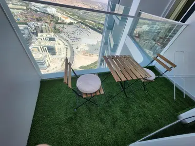 a balcony with a bench and a table and chairs at 25 Studio Skyz By Danube, Arjan in Dubai