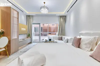 a bedroom with a large white bed and a living room at bnbmehomes - Burj Al Nujoom in Dubai