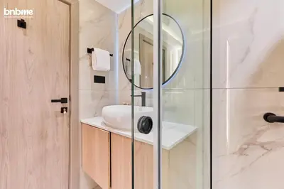 a bathroom with a shower with a sink and a mirror at bnbmehomes - Burj Al Nujoom in Dubai