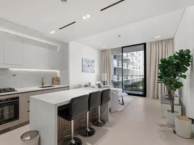 a kitchen with white walls and a island with black chairs at Modern 1BR Hideaway In Binghatti Phoenix-JVC in Dubai