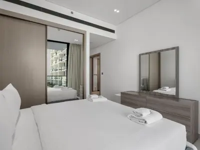 a bedroom with a large white bed and two mirrors at Modern 1BR Hideaway In Binghatti Phoenix-JVC in Dubai