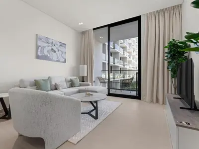 a white living room with a couch and a tv at Modern 1BR Hideaway In Binghatti Phoenix-JVC in Dubai