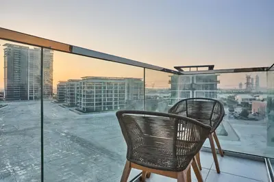 two chairs on a balcony with a view of a city at Waterfront 2BR District One Residence - Near Downtown and Lagoon in Dubai