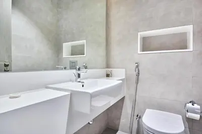 a white bathroom with a sink and a toilet at Waterfront 2BR District One Residence - Near Downtown and Lagoon in Dubai