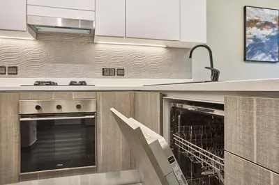 a kitchen with two ovens and a sink at Joya Blanca Residence - Bright 1BR Apartment in Arjan in Dubai