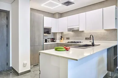 a kitchen with white cabinets and vegetables on a counter at Joya Blanca Residence - Bright 1BR Apartment in Arjan in Dubai