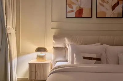 a bedroom with a bed and a nightstand with a lamp at Joya Blanca Residence - Bright 1BR Apartment in Arjan in Dubai