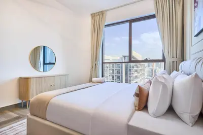 a bedroom with a large white bed with a large window at Joya Blanca Residence - Bright 1BR Apartment in Arjan in Dubai