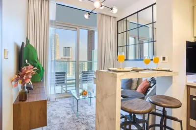 a kitchen and living room with a bar with stools at Reva Residences 1BR - Near Downtown Dubai & Canal Walk in Dubai
