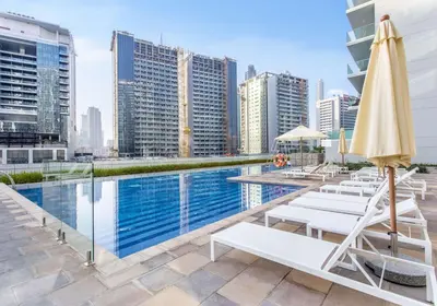 a pool with lounge chairs and an umbrella on a building at Reva Residences 1BR - Near Downtown Dubai & Canal Walk in Dubai