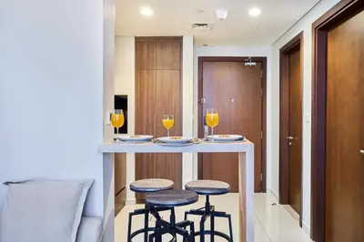 a kitchen with a bar with two glasses of orange juice at Reva Residences 1BR - Near Downtown Dubai & Canal Walk in Dubai