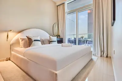 a bedroom with a large white bed and a balcony at Reva Residences 1BR - Near Downtown Dubai & Canal Walk in Dubai