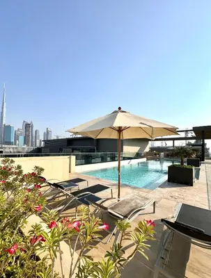 a swimming pool with an umbrella and tables and chairs at Purple Homes, City Walk Apartments in Dubai