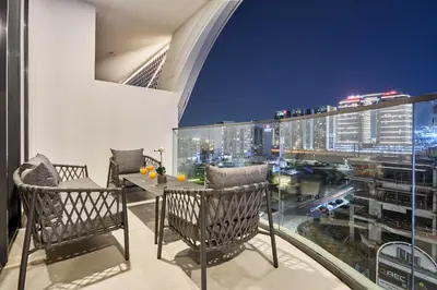 a balcony with a table and chairs and a city skyline at Stylish 1BR near Miracle Garden - Oxford Gardens in Dubai