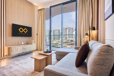 a living room with a couch and a large window at Stylish 1BR near Miracle Garden - Oxford Gardens in Dubai