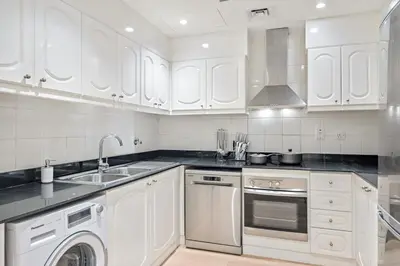 a kitchen with white cabinets and a sink and a dishwasher at FIRST CLASS 1BR Panoramic Marina Views in Dubai