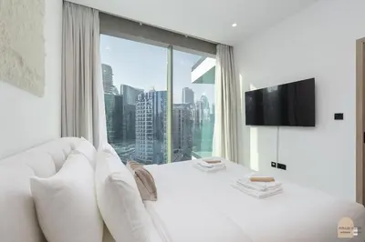 a living room with a white couch and a large window at Skyview Experience View Burj Khalifa Pool, Canal in Dubai