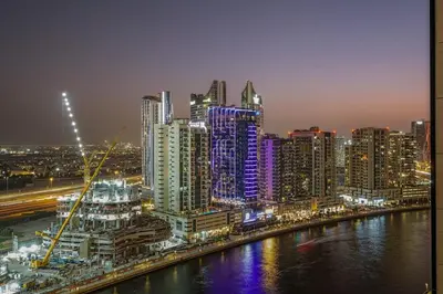 a city at night with a river and buildings at FIRST CLASS Studio Private Jacuzzi Canal View in Dubai
