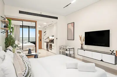 a white bedroom with a large tv on a wall at FIRST CLASS Studio Private Jacuzzi Canal View in Dubai