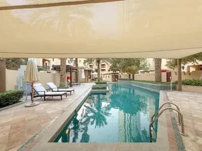 a swimming pool with two chairs and an umbrella at FIRST CLASS 2BR Old Town Burj View Retreat in Dubai