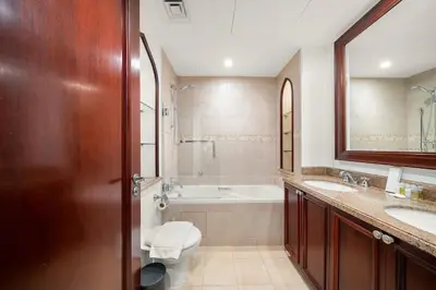 a bathroom with a tub and a toilet and a sink at FIRST CLASS 2BR Old Town Burj View Retreat in Dubai